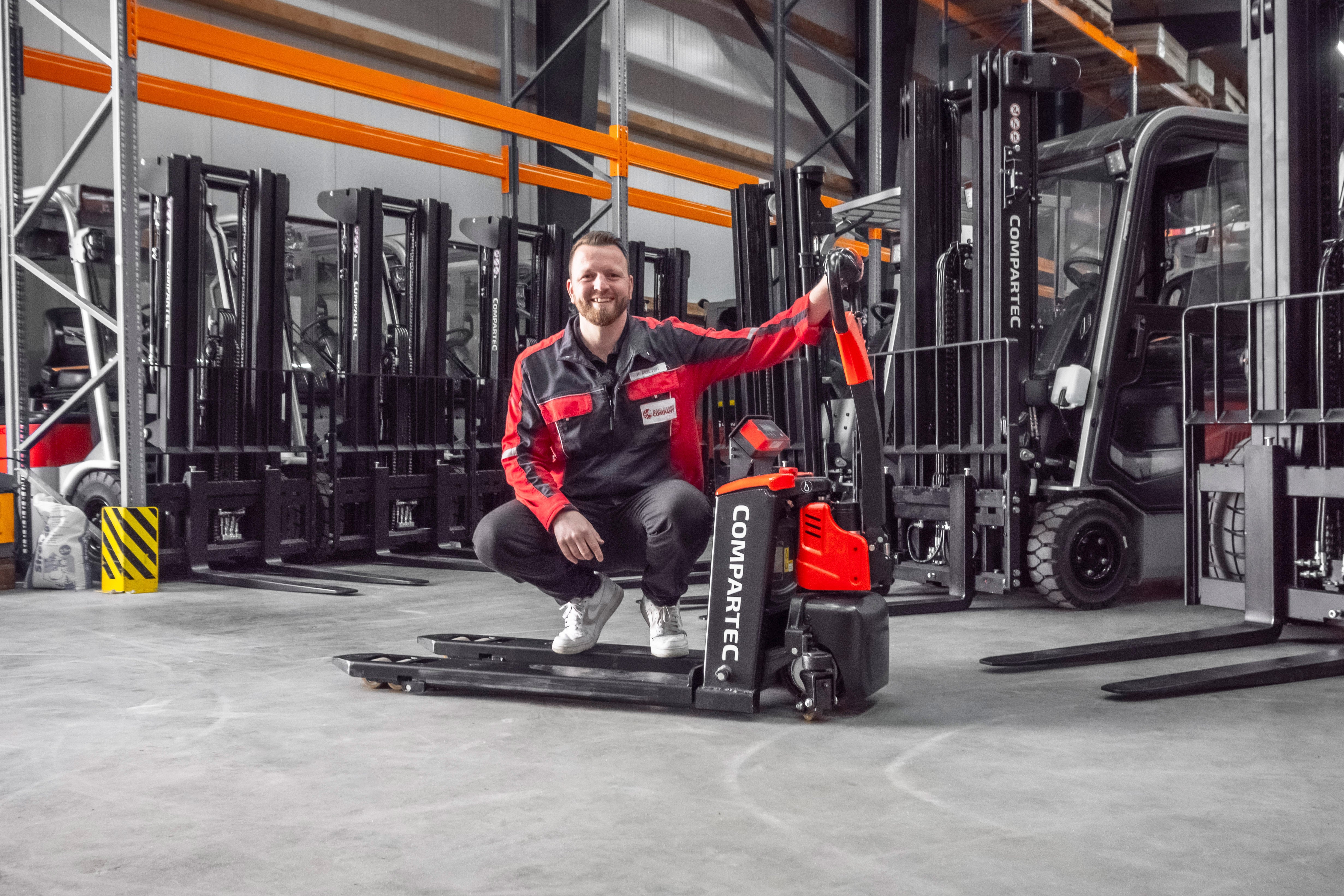 Elektrisk palleløfter på lager med gaffeltrucks og stablere i baggrunden