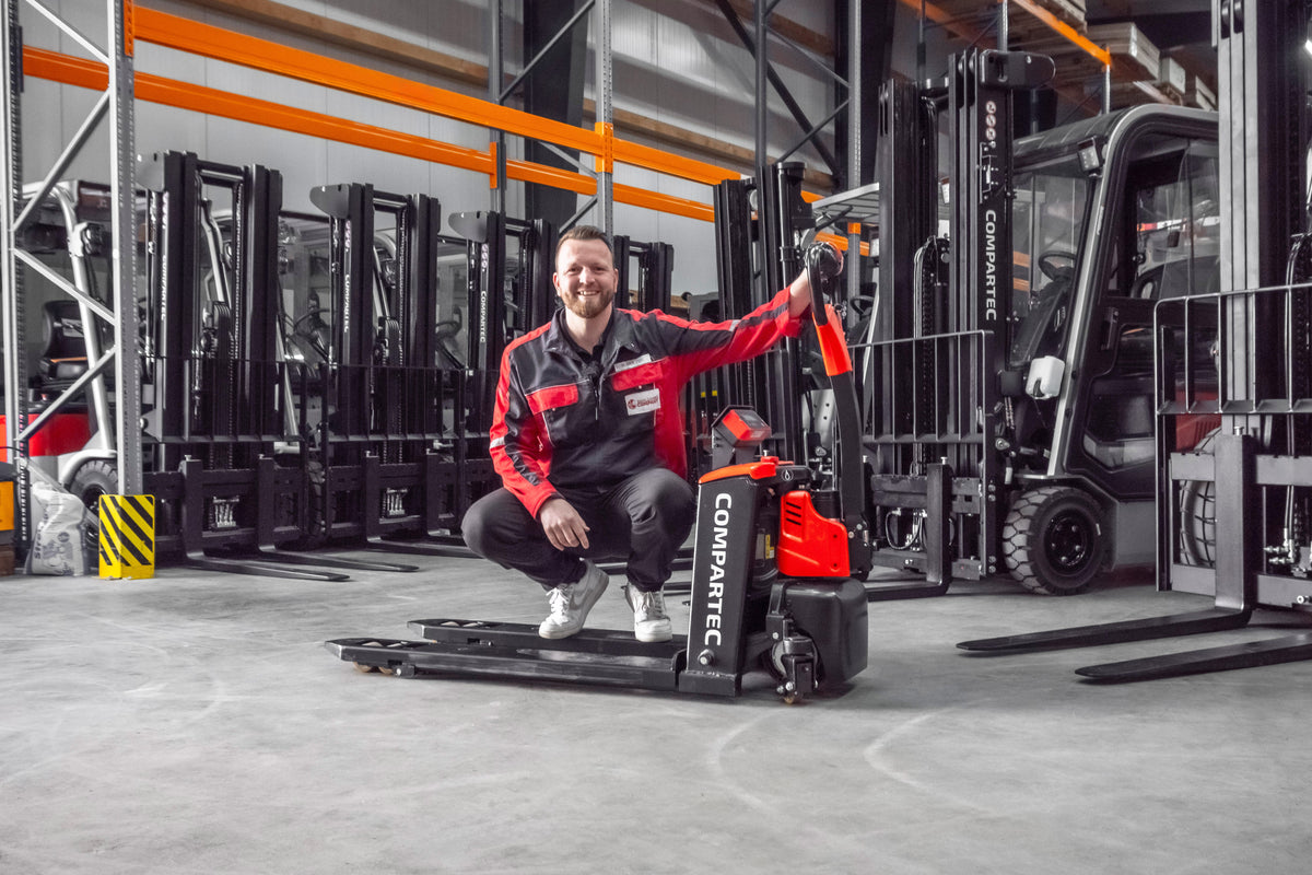 Elektrisk palleløfter på lager med gaffeltrucks og stablere i baggrunden